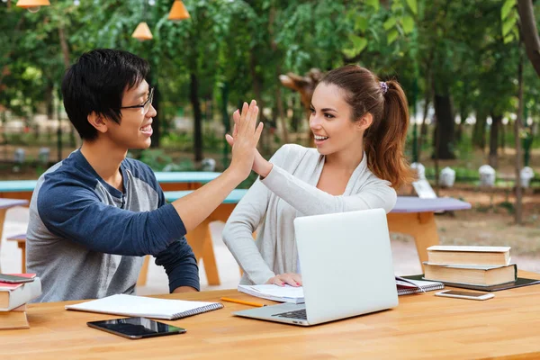Couple of students studying and giving high five outdoors — Stock Photo, Image
