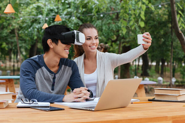 Couple using virtual reality glasses and taking selfie outdoors Stock Photo