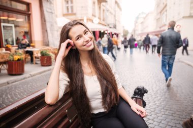 Eski şehirde bankta oturan neşeli genç kadın