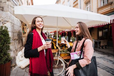 Gülüyor ve açık havada kahve içme iki neşeli kadın