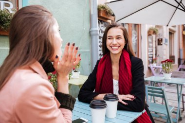 İki neşeli kadın konuşmak ve gülüyorsun açık Cafe