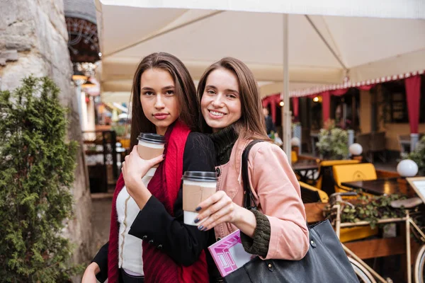 Two cheerful women standing and drinking coffee in old town — Stock Photo, Image