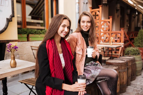 Две счастливые женщины сидят и пьют кофе в старом городе — стоковое фото