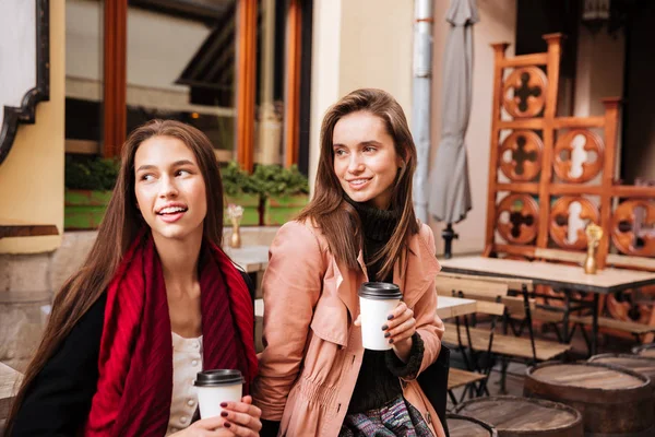 Duas mulheres sorridentes sentadas e bebendo café na cidade velha — Fotografia de Stock