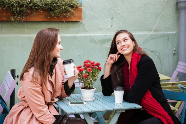 Dos mujeres sonrientes tomando café y hablando en la cafetería al aire libre —  Fotos de Stock