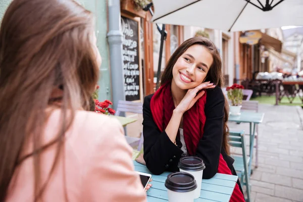 Счастливая молодая женщина разговаривает со своим другом в кафе на открытом воздухе — стоковое фото