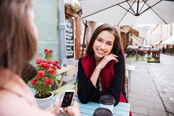 Dos mujeres hablando y utilizando el teléfono celular en la cafetería al aire libre — Foto de Stock