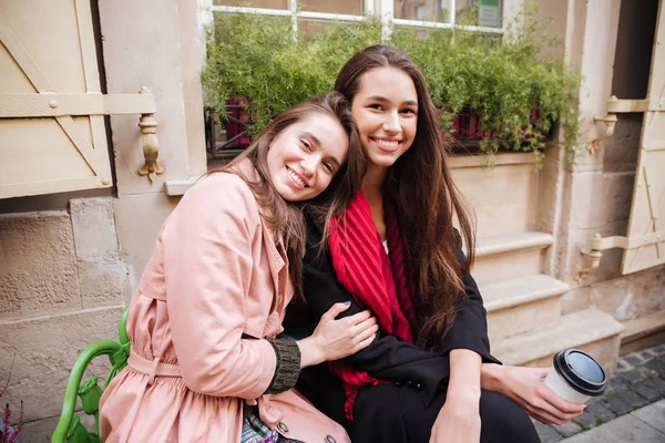 Beautiful girls in coats are sitting — Stock Photo, Image