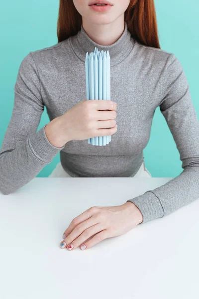 Hermosa joven sentada a la mesa y sosteniendo lápices — Foto de Stock