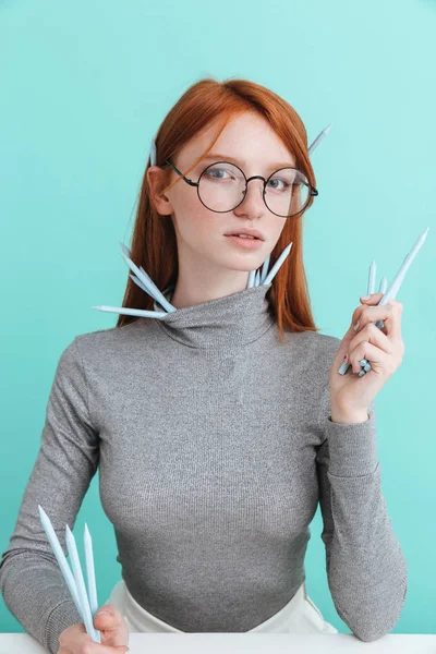 Piękna młoda kobieta w roud okulary siedzi i trzymając ołówki — Zdjęcie stockowe