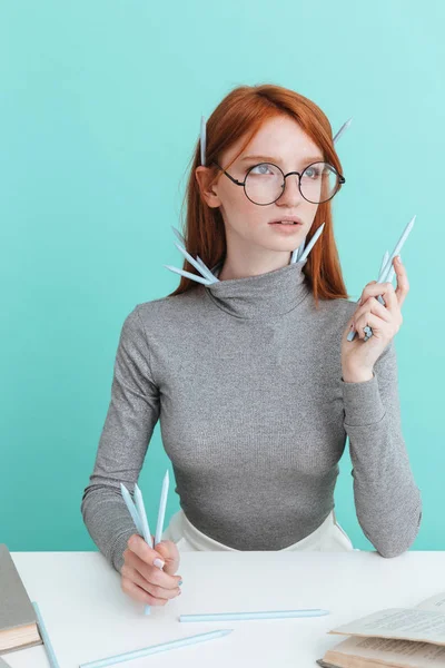 Seriózní žena s tužky posezení a čtení u stolu — Stock fotografie