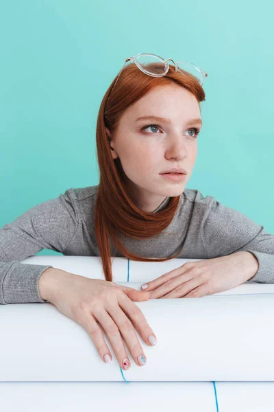 Retrato de una joven pelirroja sentada y sosteniendo planos — Foto de Stock