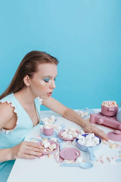 Kvinna sitter vid bordet med plasic rätter och marshmallows — Stockfoto