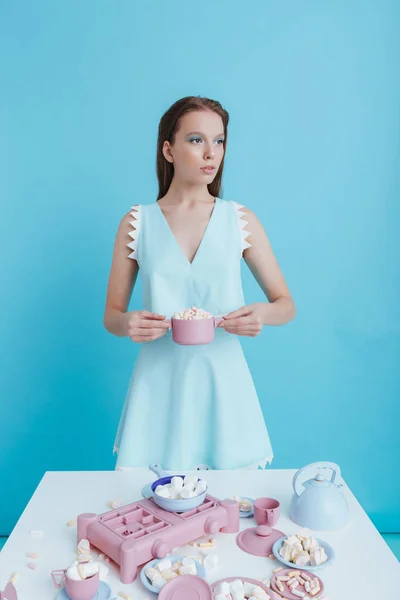 Beautiful young woman standing and holding plastic dishes with marshmallows — Stock Photo, Image