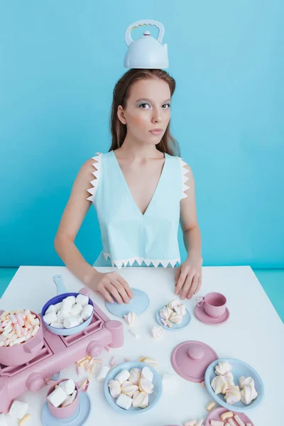 Kvinna med tekanna på huvudet spelar med marshmallows och porslin — Stockfoto