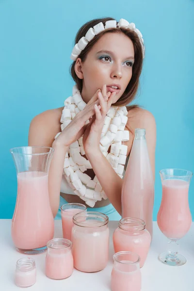 Kvinna som bär marshmallow halsband sitter vid bord med rosa dryck — Stockfoto