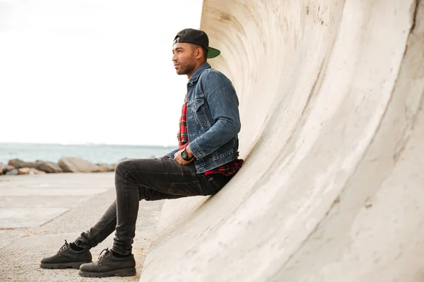 Afrikansk man bär mössa promenerar på stranden — Stockfoto