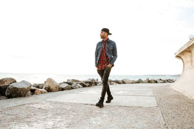 Müzik dinleme sırasında sahilde yürüyen neşeli Afrika adam