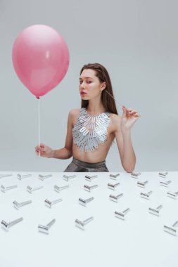 Bıçak kolye pembe balon ve büyük bir iğne tutan kadın