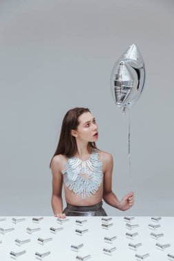 Jilet ile masada oturan kadın tutarak balon