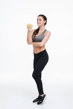 Ayakta ve elma onun elinde bakarak spor kadın