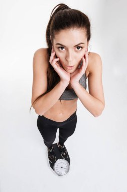 Ölçekler üzerinde duran ve kameraya bakarak sürpriz fitness kadın