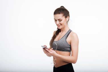Gülümseyen Fitness kadın manifatura üstünde hareket eden telefon ve kulaklık takmış