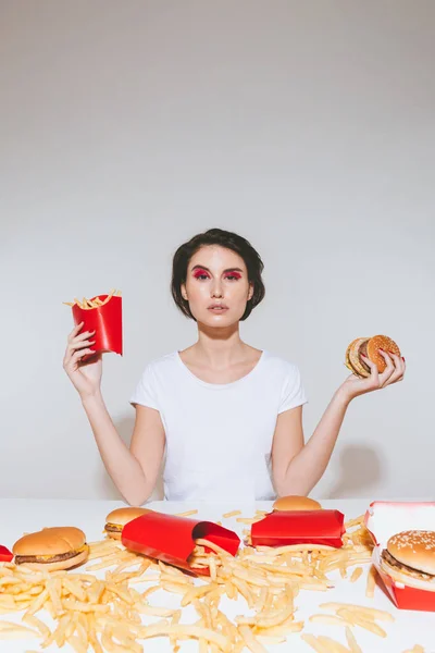 Mooie jonge vrouw houd van Franse frietjes en de hamburger — Stockfoto