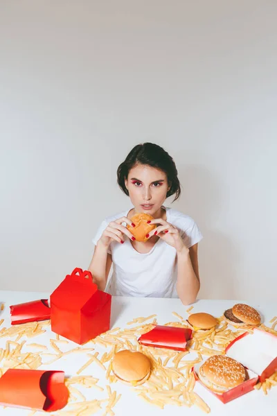 Donna affascinante mangiare hamburger dalla scatola rossa a tavola — Foto Stock