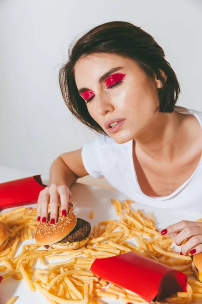 Aantrekkelijke jonge vrouw zitten aan de tafel met fast food — Stockfoto