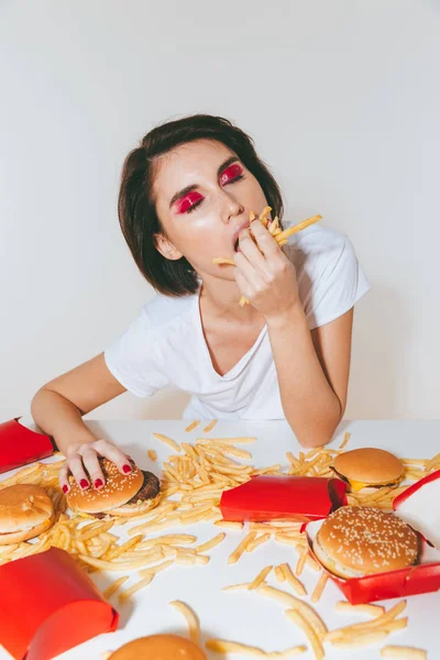 Mooie vrouw zitten aan de tafel en Franse frietjes eten — Stockfoto