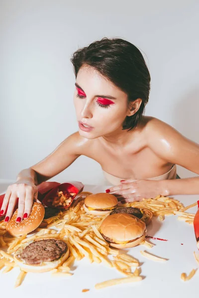 Atractiva mujer joven con maquillaje brillante comer comida rápida —  Fotos de Stock