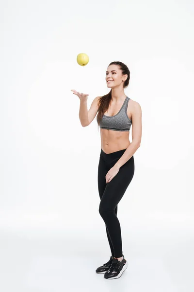 Fitness-Frau steht und wirft einen Apfel in die Luft — Stockfoto