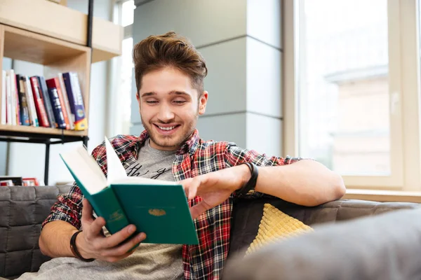Hombre feliz leyendo libro en sofá en la oficina —  Fotos de Stock