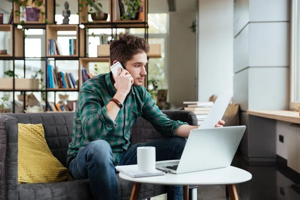 Vue de côté homme parlant au téléphone et assis à table — Photo