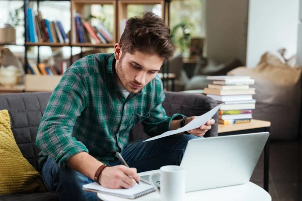 Hombre sentado en el sofá y la escritura — Foto de Stock