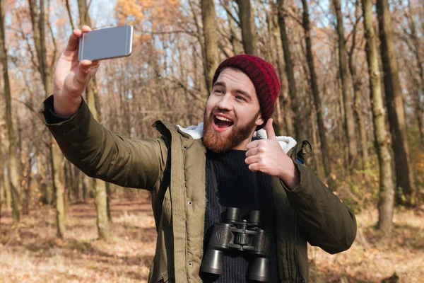 L'uomo prende selfie nella foresta mentre fa un gesto con i pollici in su — Foto Stock