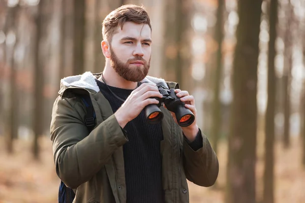 Concentrated serious bearded man holding field-glass — Stock Photo, Image