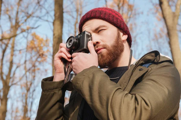 Uomo barbuto utilizzando fotocamera in piedi nella foresta . — Foto Stock