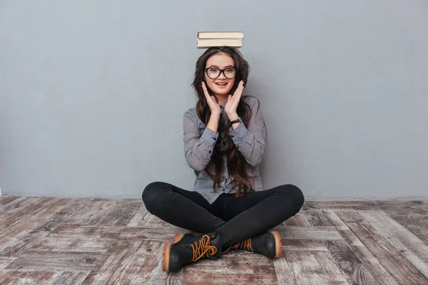 Asiatin sitzt mit Büchern auf dem Kopf — Stockfoto