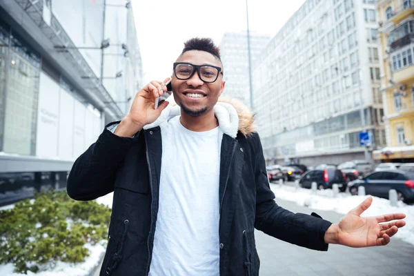 Afrikaanse jonge man lopen op straat tijdens het praten door cellphone — Stockfoto