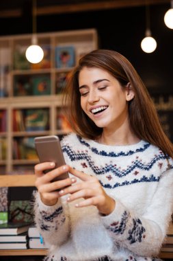 Güzel kadın manifatura Kitaplığı'nda otururken cep telefonunuzda