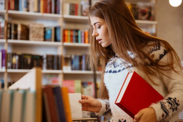 Młoda kobieta gospodarstwa książki w bibliotece — Zdjęcie stockowe