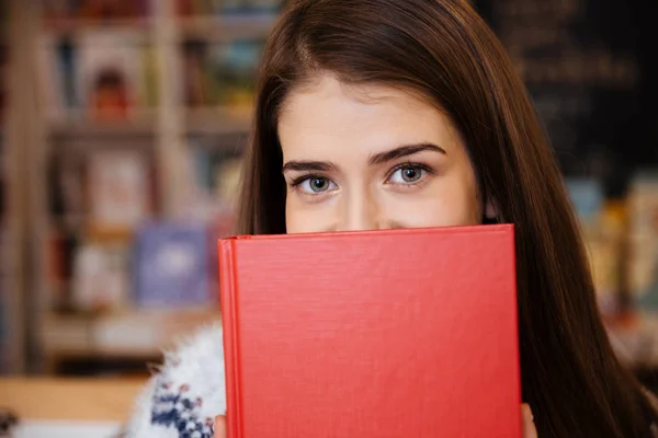 Портрет молодой женщины, закрывающей лицо книгой — стоковое фото