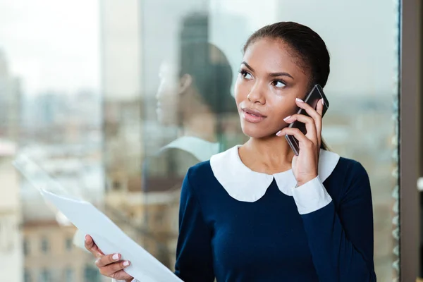 Zakenvrouw praten over telefoon in de buurt van het venster — Stockfoto