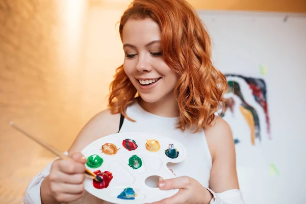 Ongelooflijke kunstschilderes met rode haren draagkracht over leeg doek — Stockfoto