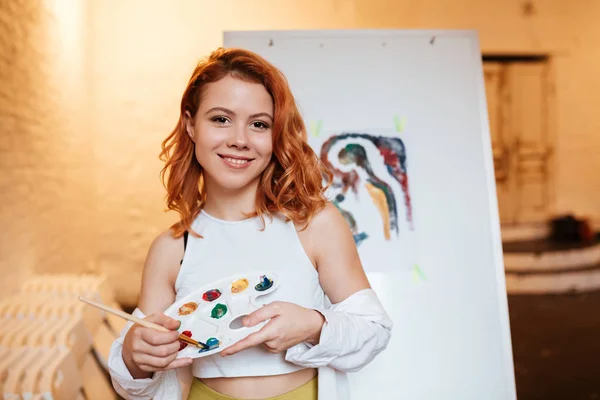 Young woman painter with red hair standing over blank canvas — Stock Photo, Image