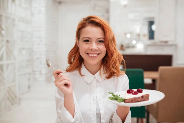 Rousse jeune femme heureuse manger gâteau dans café . — Photo