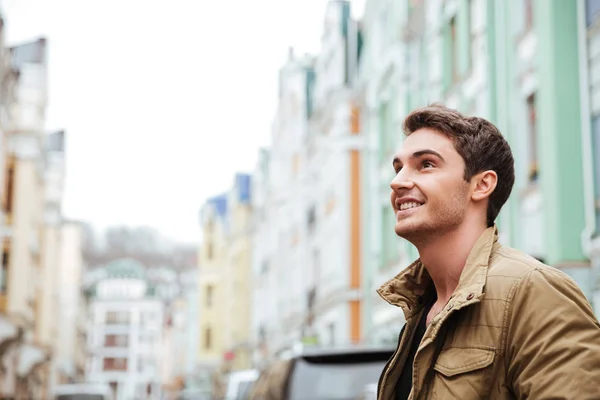 Joyful young man walking on the street and looking aside. — Stock Photo, Image