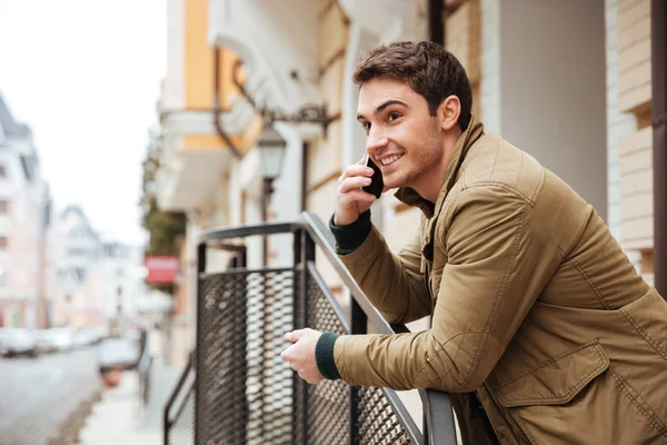 Gelukkig jonge man lopen op straat praten via de telefoon. — Stockfoto